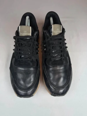 Valentino rockrunners  - Snygga svarta sneakers från Valentino med coola nitar på sidorna. Skorna har en beige sula, svarta skosnören och detaljer i både läder och mocka. Märkeslogga på plösen och en unik design som sticker ut.