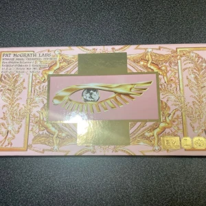 Pat McGrath ögonskuggspalett Celestial - Säljer en Pat McGrath Labs Mothership Mega: Celestial Divinity ögonskuggspalett med 18 olika nyanser. Paletten har en lyxig design i rosa och guld med ett öga på framsidan. Färgerna varierar från neutrala till färgstarka metallic och matta toner.