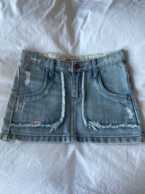 Jeanskjol  - Snygg blå jeanskjol med slitna detaljer. Köpte kjolen i Thailand och har använt dem få tal gånger. Står ingen storlek men skulle säga att den passa XS