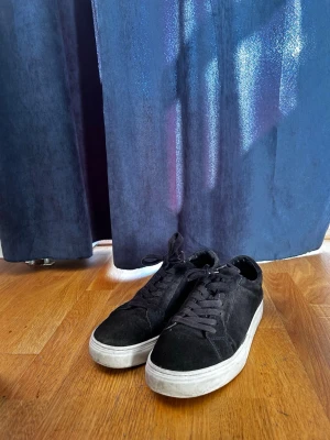 Vagabond skor  - Stilrena svarta sneakers med lågt skaft och vit sula. Skorna har klassisk snörning och är tillverkade i mockaliknande material. Perfekta för dig som gillar en enkel och clean look.