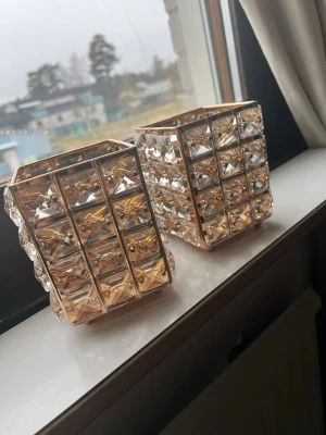 Två förvaringar  - Säljer två stilrena förvaringar för smink borstar eller pennor i fyrkantig form med guldfärgade metallramar och stora klara kristallbitar på sidorna. Matrialet är metall och vet inte riktigt vad kristallena är gjort av känns som glas. Är köpt utomlands 