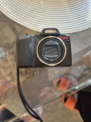 Kodak svart digitalkamera med zoom - Säljer en svart digitalkamera från Kodak med inbyggd blixt och tydligt grepp. Kameran har ett objektiv med optisk zoom och en praktisk handledsrem. Perfekt för dig som vill ta snygga bilder och gillar klassisk design.