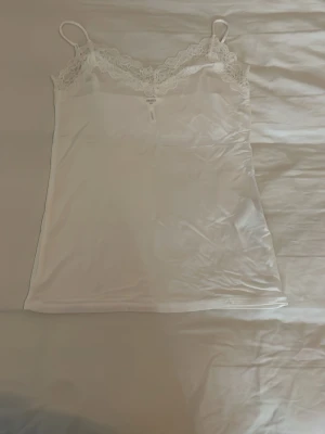 Vit spetsdetaljerad linnetopp från bikbok  - Säljer en vit linnetopp från bikbok med tunna axelband och vacker spets längs urringningen. Toppen är ärmlös och har en feminin, enkel design som passar perfekt till många olika stilar. Storlek s/m men sitter som en s!💕nästan aldrig använd men köptes för ca 1 år sen. Skriv för mer bilder eller prisförslag!💕