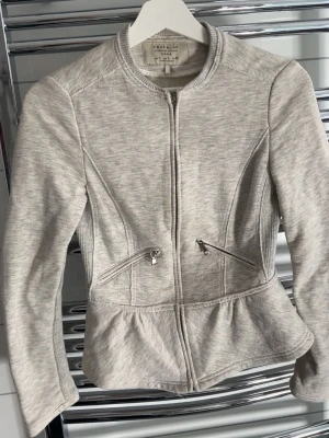 Ljusgrå zipup - Söt grå zipup med utsvägning, dragskedjan är sönder men går fortfarande att dra upp och ner som vanlig (se bild).