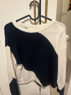 Svartvit stickad tröja med mönster - Säljer en stickad tröja i svart och vitt med coolt grafiskt mönster. Tröjan har rund halsringning och långa ärmar. Materialet känns mjukt och mysigt, perfekt för kyligare dagar. Passar dig som gillar en avslappnad men trendig stil.