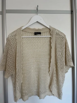 Beige virkad kofta - Kortärmad beige virkad kofta från Brittany Black. Koftan hae guldglitter i tyget så en super fin detalj. Passar mig bra som är XS/S i topp