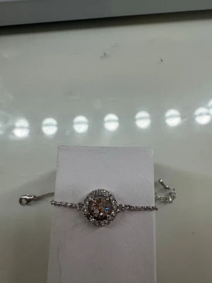 Lily and rose Silverfärgat armband med gnistrande sten - Snyggt armband i silverfärg med en rund, champagnefärgad mittsten omgiven av små klara stenar. Kedjan är tunn och elegant. Notera att en av de små stenarna saknas, men detta syns inte när den används! 💕