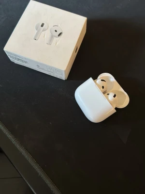 Apple AirPods med laddningsetui - Säljer ett par vita Apple AirPods med tillhörande laddningsetui. Trådlösa hörlurar med stilren och kompakt design, perfekt för musik, samtal och poddar. Kommer med originalförpackning. Smidig anslutning till iPhone och andra Apple-enheter.