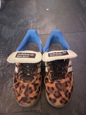 Adidas Wales Bonner leopardmönstrade sneakers - Unika Adidas Wales Bonner sneakers med leopardmönstrad ovandel i pälsimitation, vita detaljer och blått foder. Skorna har breda tungor med Wales Bonner-logga och klassiska tre ränder på sidan. Grymt statement-plagg för dig som gillar djurmönster och streetstyle.