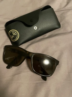 Bruna Ray-Ban solglasögon - Snygga solglasögon från Ray-Ban med bruna bågar och bruna glas. Klassisk form som passar till många stilar. Kommer med ett svart fodral i skinnimitation. Perfekta för soliga dagar och ger en cool vibe. Dem har styrka och skalet ingår ej