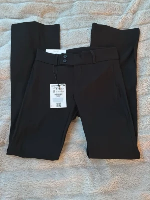 Svarta kostymbyxor från Bershka - Stilrena svarta kostymbyxor från Bershka i bootcut och två knappar i midjan. Helt oanvända! Storlek: 36 och längd: Short. (Kan byta till en större storlek antingen 38 eller 40 i längd short) 