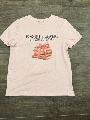 Rosa tshirt - Rosa tshirt från newyorker, med texten ”forget flowers buy books”. Aldrig använd