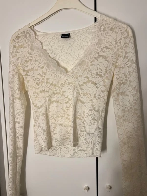 Vit spetsblus från Gina Tricot - Vit spets topp, v-ringad, med lite utsvängda ärmar längst ner. Väldigt genomskillnig så rekommenderar att ha en vit bh under. Använd kanske max 5 gånger.