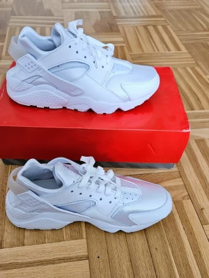 Nike Air Huarache Skor - Helt nya Nike Air Huarache – White/Pure Platinum (Stl. 41) Säljer ett par splitternya Nike Air Huarache i den stilrena färgkombinationen "White/Pure Platinum". Skorna är aldrig använda och ligger kvar i sin originalkartong. En klassisk sneaker känd för sin fantastiska komfort och ikoniska design med den stretchiga "hälremmen" som kramar om foten. Finns att hämta i Farsta. 