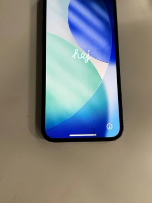 Blå iPhone 12  - Snygg blå iPhone med glasbaksida och rundade hörn. Telefonen har en stor skärm med tunna kanter och Apples klassiska logga på baksidan. Tillverkad i glas och metall, modern design som känns riktigt clean i handen. Baksidan är sprucken och framsidan har några sprickor men annars inga fel. Fungerar precis som vanligt. Bara att skriva om jag ska skicka fler bilder eller liknande!!