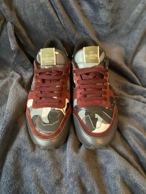 Valentino Rockrunner - Snygga Valentino Rockrunner sneakers med vinröda, svarta och grå camouflagemönster. Jag vet ej exakt vad storleken är men den passar till storlek 42-43, innersulan är 27,5cm. Skriv vid frågor. Mvh