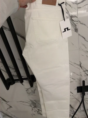 Vita raka jeans från J.Lindeberg - HELT NYA!! Säljer ett par stilrena vita jeans från J.Lindeberg. Jeansen har rak passform, klassisk femficksdesign och är tillverkade i ett mjukt bomullstyg. Perfekta för en clean och modern look. W34 L32