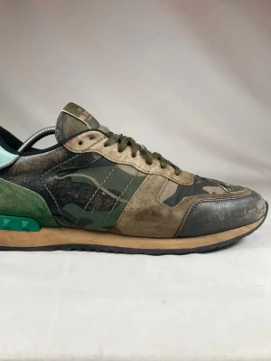 Valentino rockrunners  - Snygga sneakers från Valentino med camomönster i grönt, brunt och svart. Skorna har detaljer i mocka och läder, samt en unik grön detalj på hälen. 