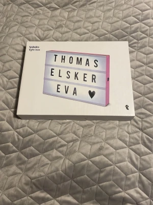 Ljusbox med bokstäver rosa/vit - Snygg ljusbox i plast med rosa ram och vit front där du kan sätta in egna bokstäver och symboler för att skapa personliga meddelanden. Perfekt som dekoration i rummet eller till events. Inkluderar bokstäver, siffror och symboler för att variera texten.