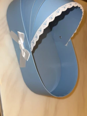 Blå dekorativ vagga med rosor - Säljer en blå dekoration formad som en vagga, dekorerad med vit spetskant och en vit rosett på sidan. Inuti finns blå konstgjorda rosor som ger en söt och unik look. Perfekt som present eller bordsdekoration till babyshower eller dop. Har 3 stycken