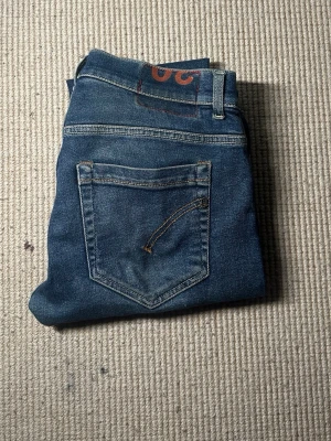 Blå slim fit jeans från dondup - Säljer ett par blå slim fit jeans från dondup med klassisk femficksdesign och läderpatch bak i midjan. Jeansen har en snygg tvättad look och smala ben. Perfekta för dig som gillar en enkel men stilren stil. W 30 tror jag, notera att de finns lite färg på jeansen. Annars är dem väldigt bra skick och sjukt snygga. Kontakta för priset och mera✌️❄️💤