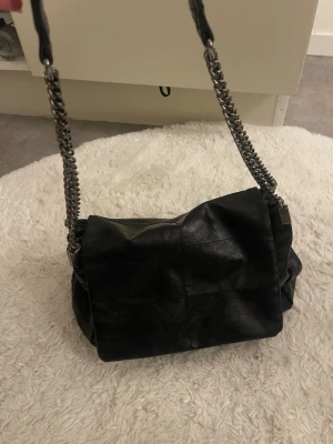 Svart handväska med kedjerem - Snygg svart axel väska från Zara med axelrem i silverkedja. Väskan är SNYGG och OTROLIGT rymlig. Men den kommer inte till användning för mig därför säljer jag den nu
