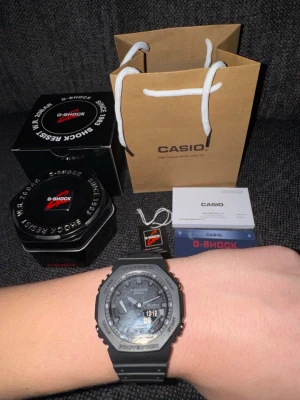 Svart Casio G-Shock klocka - Säljer en svart Casio G-Shock klocka med digital och analog display. Klockan har robust design, svart resinarmband och kommer med originalförpackning, manual. Perfekt för dig som gillar sportig och tålig stil.