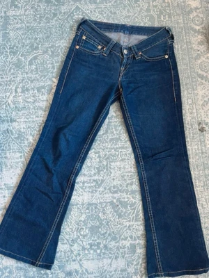 Blå bootcut jeans från Levi's - Säljer ett par klassiska blå bootcut jeans från Levi's. Jeansen har låg midjade och är typ ”V-ringad”. Jag skulle säga det är en S/M men kanske lite mer åt M hållet :) Tveka inte på att kontakta vid frågor 💙