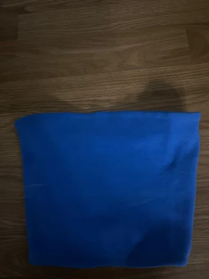 Blå bandeau topp från Zara - Säljer en enkel och stilren blå bandeau topp från Zara. Toppen är axelbandslös och har en tight passform som sitter snyggt på kroppen. Perfekt att matcha med höga jeans eller kjol för en clean look.