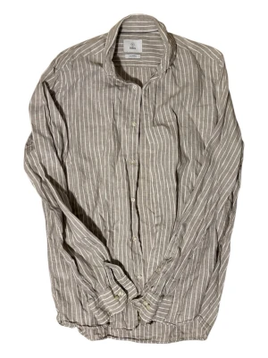 Randig linneskjorta från Blåck - Snygg grå skjorta från Bläck i luftigt linne med vita vertikala ränder. Klassisk krage, knäppning framtill och långa ärmar. Perfekt för en avslappnad men stilren look.