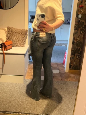 Blå bootcut jeans från True religion - Säljer ett par blå bootcut jeans från True religion med låg midja i Joey, storlek w26. Säljer eftersom de är för stora. Ena benet har ett litet hål men annars är byxorna som fint. 