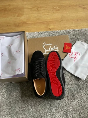 Svarta Christian Louboutin sneakers - Snygga svarta sneakers från Christian Louboutin med klassisk röd sula och svarta skosnören.              Helt nya skor aldrig använda eller testade. Finns flera storlekar 42,43,44. OBS säljer slut snabbt. Pris kan diskuteras vid snabb affär 