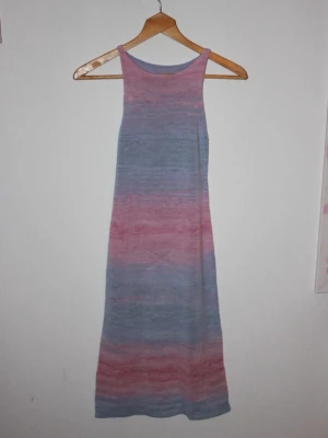Pastellfärgad långklänning - Långklänning i mjuka pastelltoner av blått, rosa och lila. Klänningen har ärmlös design med raka axelband. Perfekt för sommarens varma dagar och ger en avslappnad men ändå stilren look.