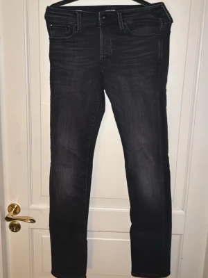Svarta slim jeans Jack & Jones - Snygga svarta slim fit jeans från Jack & Jones, modell Glenn. Jeansen har klassisk femficksdesign, smal passform och subtila slitningar för en modern look. Perfekta för dig som gillar stilrena och bekväma jeans. 28 i midjan och 32 i längden. Pris kan diskuteras, skriv till mig. Finns att hämta i Torslanda eller så fraktar jag.