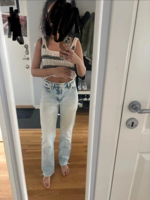 Ljusblå raka jeans med hög midja - Säljer ett par ljusblå jeans med raka ben och hög midja. Jeansen har klassisk femficksdesign och är tillverkade i denim med en lätt tvättad look. Perfekta för en avslappnad och trendig stil.