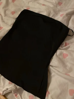 Svart axelbandslös kort topp - En stilren svart axelbandslös topp med kort längd och enkel design. Perfekt för dig som gillar minimalistisk stil och vill ha en klassisk bas i garderoben.