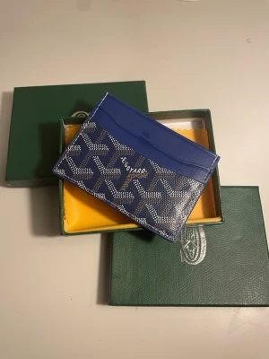 Blå kortfodral från G4yard - Snyggt blått kortfodral från G4yard med klassiskt mönster och logga framtill. Tillverkat i läder med flera kortfack och stilren design. Perfekt för dig som vill ha något exklusivt och trendigt i fickan.
