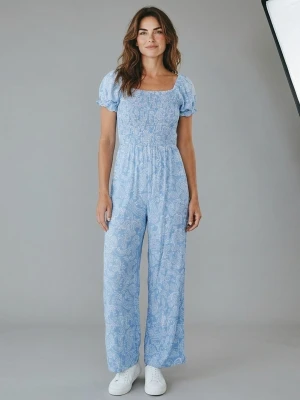 Blå mönstrad jumpsuit från Kappahl 152 - Supersöt blå jumpsuit från Kappahl med vitt paisleymönster. Modellen har korta puffärmar, smockad överdel och vida ben. Perfekt för dig som gillar en avslappnad men trendig stil. Tillverkad i mjukt och lätt tyg som känns skönt mot huden.
