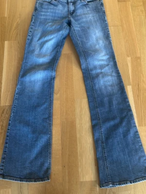Blå bootcut jeans från RW&CO - Snygga blå bootcut jeans från RW&CO i klassisk tvätt. Jeansen är tillverkade av 98% bomull och 2% elastan för en bekväm stretch. De har normal midja och utsvängda ben, perfekta för en avslappnad och trendig look.