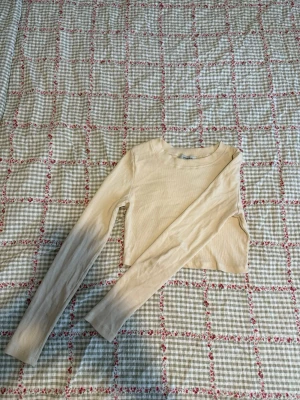 Beige ribbad croppad topp Chiquelle - Säljer en beige ribbad croppad långärmad topp från Chiquelle. Toppen har en enkel och stilren design med rund halsringning och är tillverkad i ett mjukt, stretchigt material som sitter snyggt på kroppen.