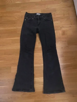 Svarta bootcut jeans  - Säljer ett par svarta bootcut jeans med låg midja  och klassiska fem fickor. Jeansen har utsvängda ben och är tillverkade i ett mjukt denimtyg. Perfekta för dig som gillar retrovibbar och vill ha en snygg siluett.