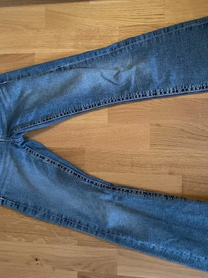 Blå  low waist bootcut jeans - Säljer ett par klassiska blå jeans med utsvängda ben och låg midja. 