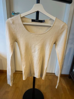 Beige stickad tröja Vero Moda - En stilren beige stickad tröja från Vero Moda med rund, djup ringning och långa ärmar. Tröjan är tunnstickad och har en klassisk, figurnära passform som passar perfekt till många olika outfits.