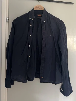 Morris skjorta - Snygg mörkblå skjorta från Morris i 100% linne. Skjortan har vita knappar och klassisk krage. Perfekt för en stilren och avslappnad look.