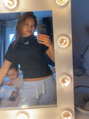 Svart ribbad croppad topp - Säljer en svart croppad topp med ribbad struktur. Toppen har korta ärmar och en tight passform som framhäver midjan. Perfekt till jeans eller kjol för en trendig look.