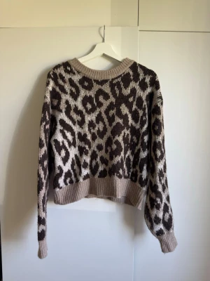 Leopardmönstrad stickad tröja Gina Tricot - Stickad tröja från Gina Tricot i beige och brunt med leopardmönster. Tröjan har rund halsringning, ribbade muddar och avslappnad passform. 