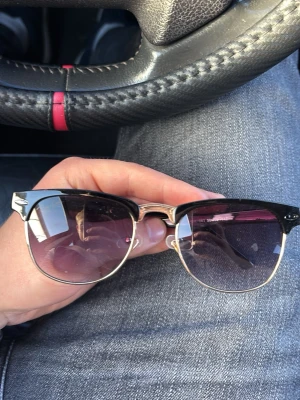 Svarta Ray-Ban solglasögon Clubmaster - Säljer ett par klassiska Ray-Ban Clubmaster solglasögon i svart med silvriga detaljer. Snygg retroinspirerad båge i plast och metall som ger en tidlös look. Perfekta för dig som vill ha en ikonisk accessoar till sommaren.