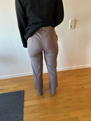 Bruna kostymbyxor med rak passform - Snygga bruna kostymbyxor med hög midja och raka ben. Byxorna har klassisk knapp- och dragkedjestängning framtill samt diskreta fickor i sidorna. Perfekta för en stilren och trendig look.