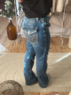 Blå bootcut jeans med broderade fickor - Säljer ett par superfina jeans från GinaTricot med detaljer på bakfickorna, detta är i storlek 170 och jag är ca 160cm lång. Hålen på framsidan är själv gjorda om jag inte minns fel💕De är i superfint skick och använda några fåtal gånger