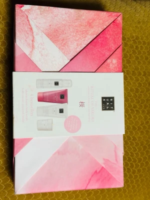 Rituals The Ritual of Sakura presentbox - Lyxig presentbox från Rituals med serien The Ritual of Sakura. Innehåller fyra bästsäljande produkter: duschgel, kroppskräm, kroppsskrubb och doftljus. Förpackningen är rosa och vit med geometriskt mönster – perfekt för dig som älskar self-care och fina detaljer.